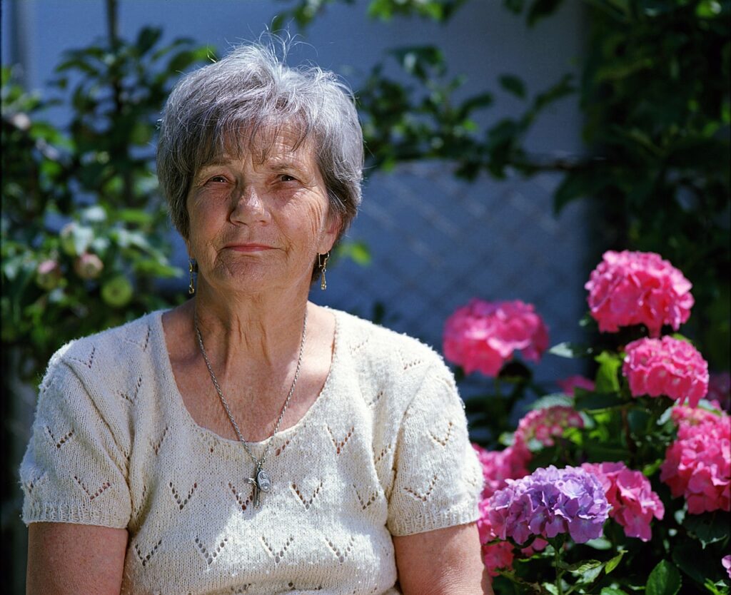 Elderly woman smiling while applying Xitox Foot Pads to her feet at home before bedtime